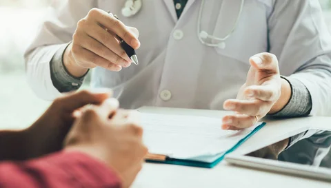 Eine Person im Kittel schreibt etwas auf ein Blatt Papier.