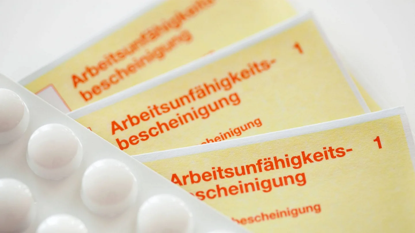 Arbeitsunfähigkeitsbescheinigungen, im Vordergrund liegt eine Packung Tabletten