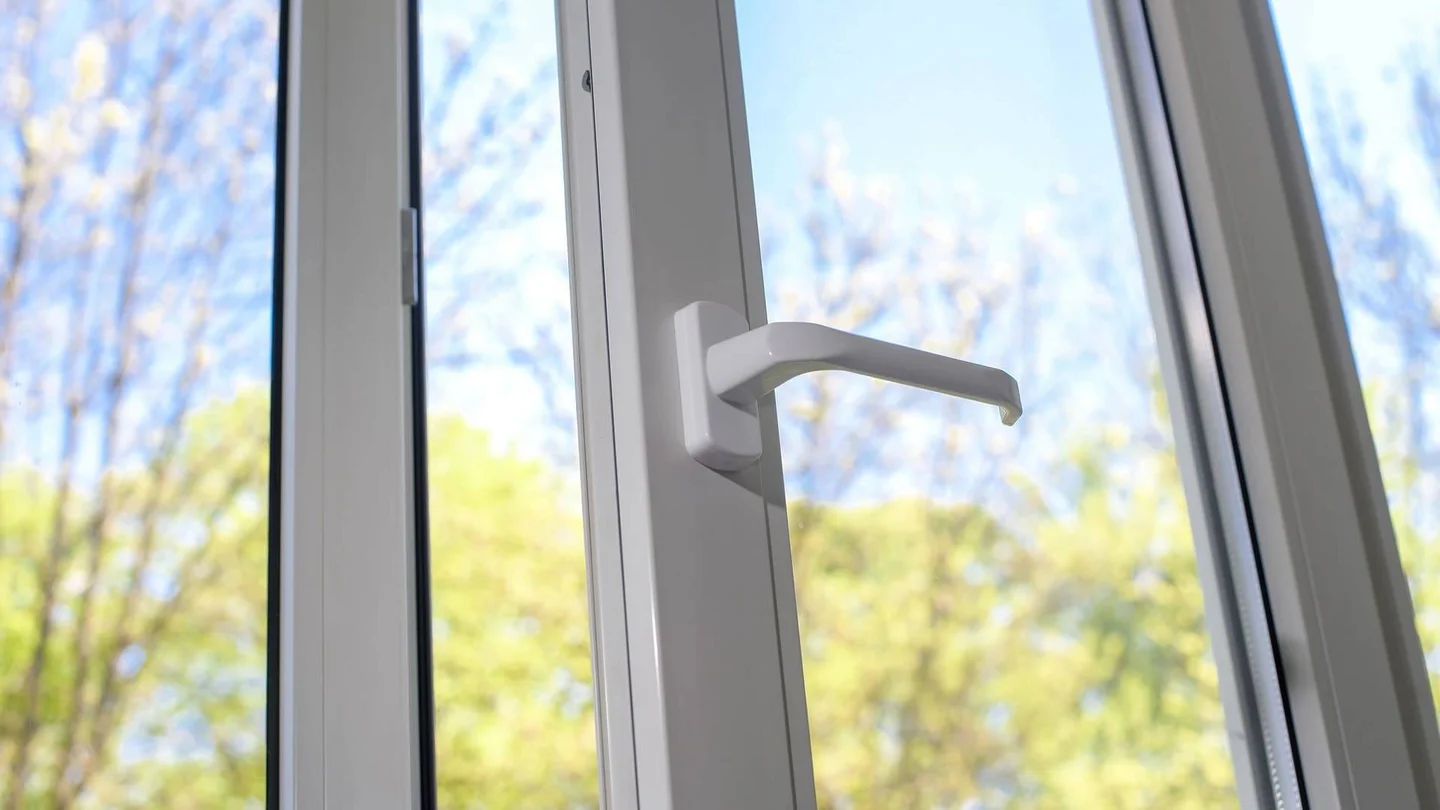 Ein Fenster steht offen. Im Hintergrund sind Bäume und ein blauer Himmel zu sehen.