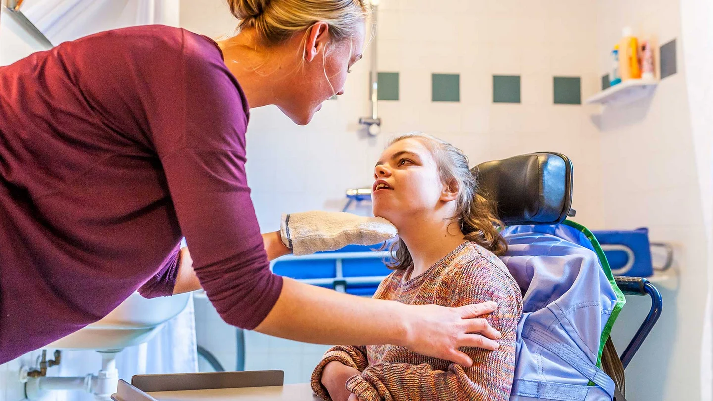 Eine Frau betreut ein junges M&auml;dchen in einem elektronischen Rollstuhl.