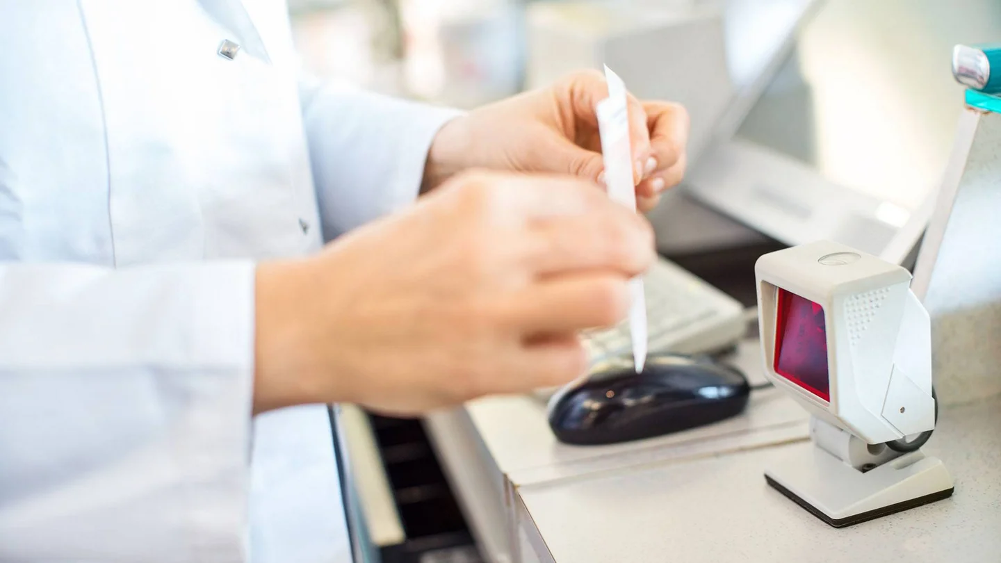 Apothekerin scannt einen QR-Code, der auf einem Rezept aufgedruckt ist.