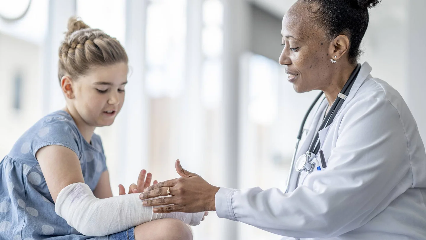 Eine Ärztin prüft den eingegipsten Arm eines Mädchens.