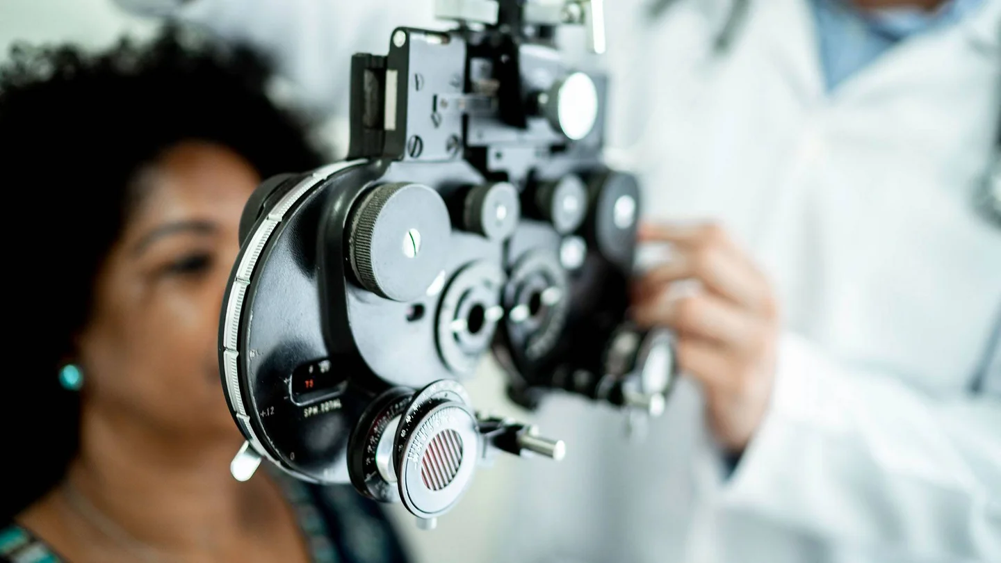 Eine Frau sitzt hinter einem Messger&auml;t f&uuml;r einen Sehtest.