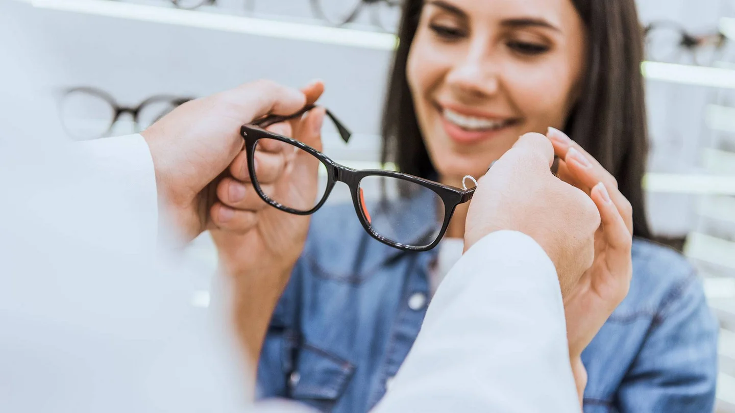 Junge Frau bekommt Brille vom Optiker