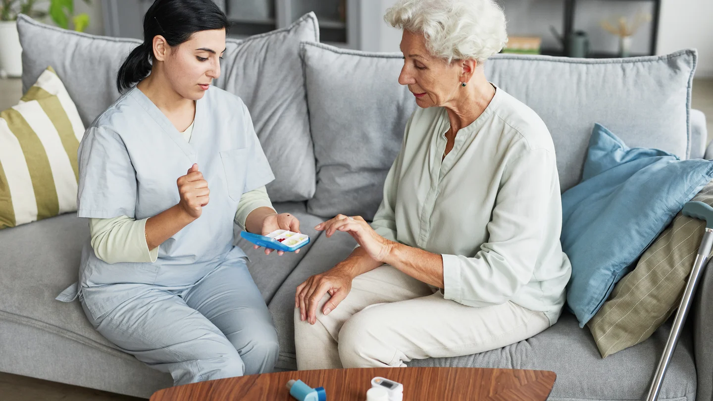Ältere Frau und Pflegekraft prüfen Tabletten.