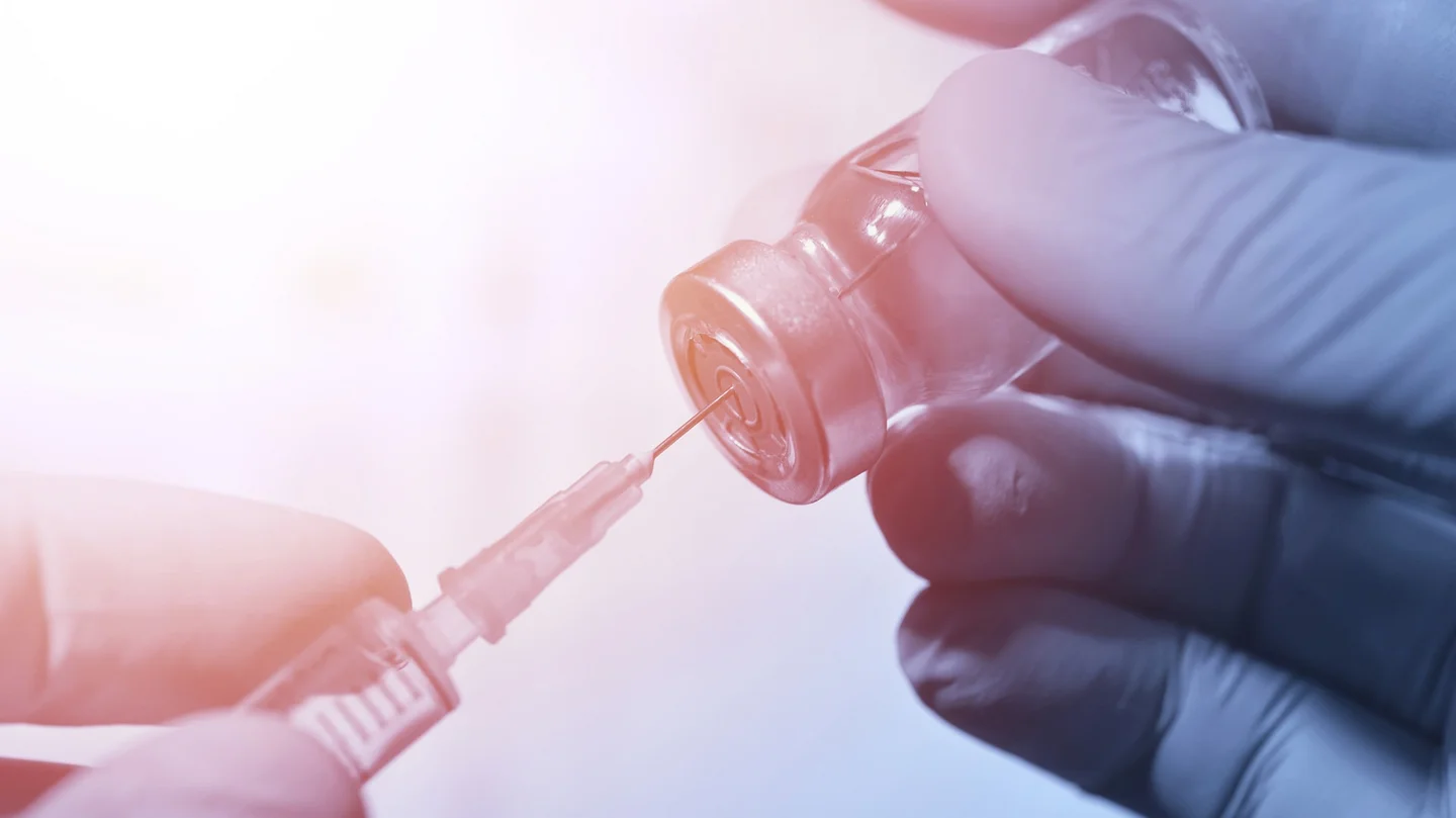 Nahaufnahme einer Aufziehkanüle, die in einer Impflösung steckt