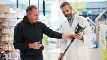 Verkäufer und Kunde mit einer Gehhilfe.