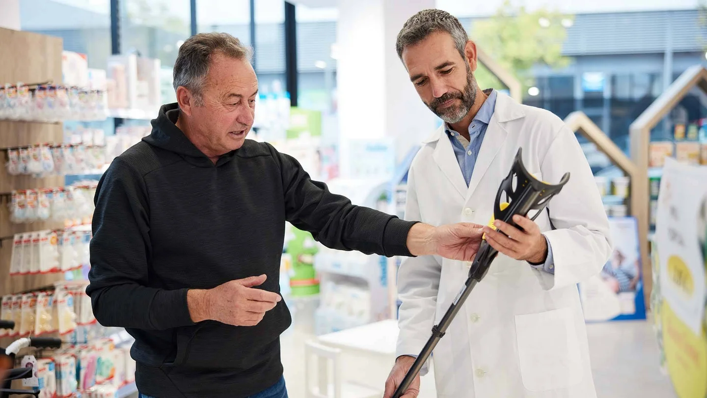 Verkäufer und Kunde mit einer Gehhilfe.